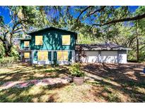 Charming two-story home with a lush, green lawn and mature trees at 9724 Hermit Hollow Ln, Gibsonton, FL 33534