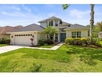 Charming two-story home featuring manicured lawn, lush landscaping, and a welcoming front entrance with a three car garage at 10142 Deercliff Dr, Tampa, FL 33647