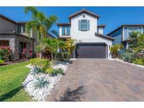 Two-story home boasts a brick-paved driveway, a two-car garage, and lush tropical landscaping at 19554 Roseate Dr, Lutz, FL 33558
