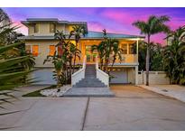 Stunning multi-story home with a grand staircase, lush landscaping, and dual garages at 294 Kentucky Ave, Crystal Beach, FL 34681