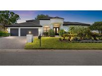 Beautiful single-story home featuring a well-manicured lawn, three-car garage, and a charming entryway with detailed landscaping at 30247 Fairway Dr, Wesley Chapel, FL 33543