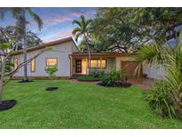 Charming single-story home with a lush green lawn, mature trees, and a well-maintained landscape at 4926 Camellia S Way, St Petersburg, FL 33705