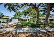 Charming single-story home featuring a well-maintained lawn, mature trees, and a two-car garage at 7241 56Th N Ave, St Petersburg, FL 33709