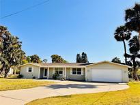 Charming single-story home with a well-manicured lawn, attached garage, and decorative shutters on a sunny day at 754 Seminole Blvd, Tarpon Springs, FL 34689