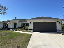 Charming home featuring a two-car garage, well-maintained lawn, and an American flag at 12021 Coleman Ave, Port Charlotte, FL 33981
