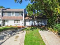 Charming townhome featuring a well-maintained lawn, mature landscaping, and inviting curb appeal at 1236 Abbey Crescent Ln, Clearwater, FL 33759