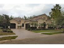 Stunning single-story home featuring a paver driveway, tile roof, and lush landscaping at 1509 Amarone Pl, Lutz, FL 33548