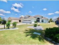 Beautiful single-story home with manicured lawn, charming landscaping, and a two-car garage on a sunny day at 1613 E Del Webb Blvd, Sun City Center, FL 33573