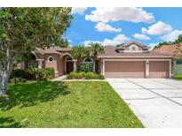 Charming home featuring a three-car garage and well-manicured lawn with mature landscaping at 27054 Fordham Dr, Wesley Chapel, FL 33543