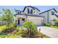 Charming two-story home features a two-car garage, manicured lawn, and lovely landscaping at 31966 Asbury Ave, Wesley Chapel, FL 33545