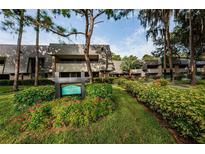 Inviting exterior of Carnoustie condos with lush landscaping, mature trees, and a welcoming sign at 36750 Us 19 N # 3-124, Palm Harbor, FL 34684
