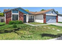 Charming single-story home features a brick facade and well-maintained front lawn with stepping stones at 747 Stillview Cir, Brandon, FL 33510