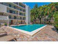 Beautiful community pool with lounge chairs and tables surrounded by lush tropical landscaping at 105 4Th Ne Ave # 220, St Petersburg, FL 33701