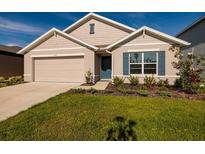 Charming single-Gathering home featuring a manicured lawn, blue shutters, and a two-car garage at 1304 Tahitian Sunrise Dr, Plant City, FL 33565