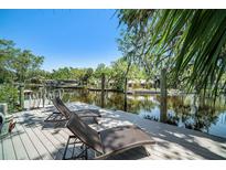 Inviting waterfront dock features two lounge chairs with stunning views of the waterway and surrounding natural landscape at 5910 River Rd, New Port Richey, FL 34652