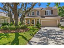 Charming two-story home featuring a well-manicured lawn, mature landscaping, and a welcoming two-car garage at 13312 Tiger Lilly Ln, Tampa, FL 33625