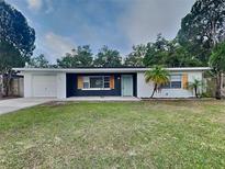Charming single-story home with a well-manicured lawn, an attached garage, and a light-blue front door at 1361 Overlea St, Clearwater, FL 33755
