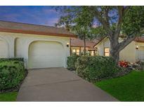 Inviting home featuring a two-car garage, well-maintained landscaping, and classic architecture at 14926 Feather Cove Rd, Clearwater, FL 33762
