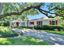 Charming single story home with white brick, red shutters, and mature landscaping at 1603 Cottagewood Dr, Brandon, FL 33510
