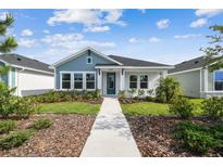 Charming single-story home with a blue accent and beautifully landscaped front yard at 28776 Rambutan Dr, Wesley Chapel, FL 33543