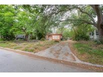 View of a quaint home with a long driveway surrounded by mature trees and lush greenery at 3027 W Helen Ave, Tampa, FL 33611