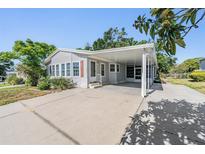 Well-maintained single-story home with a covered carport and a neatly paved driveway at 37422 Neukom Ave, Zephyrhills, FL 33541