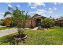 Charming single-story home with a well-manicured lawn and lush landscaping and two-car garage at 6006 Chellas Ct, Lutz, FL 33558