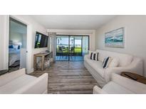 Bright living room featuring a peek of the beach, sliding glass doors, light colored couch, and light wood floors at 6265 Sun Blvd # 115, St Petersburg, FL 33715