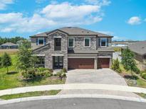 Charming two-story home featuring a stone facade, three-car garage, and meticulously landscaped front yard at 12795 Fisherville Way, Riverview, FL 33579