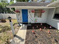 Charming home entrance with vibrant blue door, decorative accents, and well-maintained landscaping at 1407 College Park Ln, Tampa, FL 33612