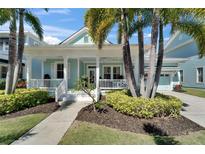 Charming light blue home featuring a welcoming front porch, lush landscaping, and a well-maintained lawn at 426 Islebay Dr, Apollo Beach, FL 33572
