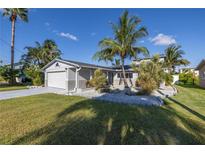 Charming single-story home with a well-manicured lawn and lush tropical landscaping in a waterfront community at 533 Lillian Dr, Madeira Beach, FL 33708