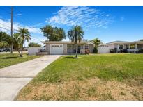 Charming single-story home with a well-manicured lawn, driveway, and tropical landscaping at 5800 Dartmouth N Ave, St Petersburg, FL 33710