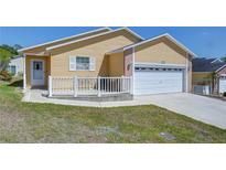 Charming single-story home with yellow siding, a white garage door, and a small front porch at 5906 Greenbriar Ct, Zephyrhills, FL 33542