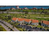Scenic aerial view of condos with a red-tiled roof, surrounded by a golf course and blue waters in the background at 6191 Bahia Del Mar Blvd # 103, St Petersburg, FL 33715