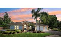 Charming single-story home with a three-car garage, lovely landscaping, and a beautiful sunset backdrop at 6901 Arabian Rd, Odessa, FL 33556