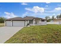 Beautiful single-story home featuring a three-car garage, modern design, and well-maintained landscaping at 7372 Madrid Rd, Weeki Wachee, FL 34613