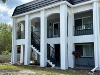 A bright white condominium with gray trim, black railings, and stairs leading to the second floor entry at 8651 10Th N St # 236, St Petersburg, FL 33702
