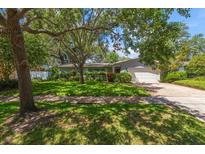 Charming single-story home with lush green lawn and mature trees offering shade at 1340 Whispering Pines Dr, Clearwater, FL 33764