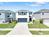 Charming two-story home featuring a well-manicured lawn, two-car garage, and classic architectural details at 636 Sunlit Coral St, Ruskin, FL 33570