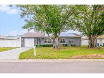 Charming single-story home with gray siding, a well-manicured lawn, and mature trees in a residential neighborhood at 7111 13Th E St, Sarasota, FL 34243