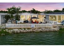 Charming waterfront home with a white picket fence, gazebo, and multiple seating areas overlooking the water at 8444 Fantasia Park Way, Riverview, FL 33578