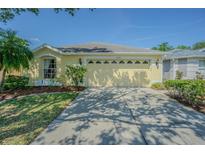 Charming one-story home with a well-manicured lawn, sunny yellow paint and attached two car garage at 10809 Collar Dr, San Antonio, FL 33576