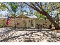 Charming single-story home with a walled courtyard, flag, and lush tropical landscaping at 110 Parkside Colony Dr, Tarpon Springs, FL 34689
