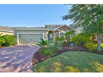 Charming single Gathering home with a beautifully landscaped front yard and brick paver driveway at 12206 Blue Pacific Dr, Riverview, FL 33579