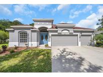 Charming single-Gathering home features a three-car garage, landscaped lawn, and stylish blue double-door entry at 3527 101St E Ave, Parrish, FL 34219