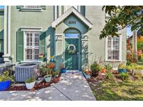 Charming home featuring a vibrant green front door with decorative wreath and lovely potted plants lining the walkway at 9828 Lake Chase Island Way # 0, Tampa, FL 33626