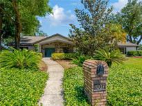 Charming single-story home featuring a well-manicured lawn, mature trees, and a welcoming walkway to a decorative front door at 1007 Morfield Ln, Brandon, FL 33511