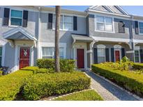 Charming townhome exterior with well-manicured bushes and a striking red front door at 309 Countryside Key Blvd, Oldsmar, FL 34677