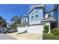 Charming two-story townhome with a two-car garage and a well-manicured lawn on a bright day at 423 Birdsong Ln, Dunedin, FL 34698